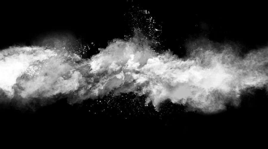 White powder dissipating in air against black background.
