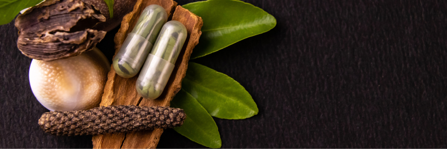 An image of nutritious food next to two capsules filled with green leafy material.