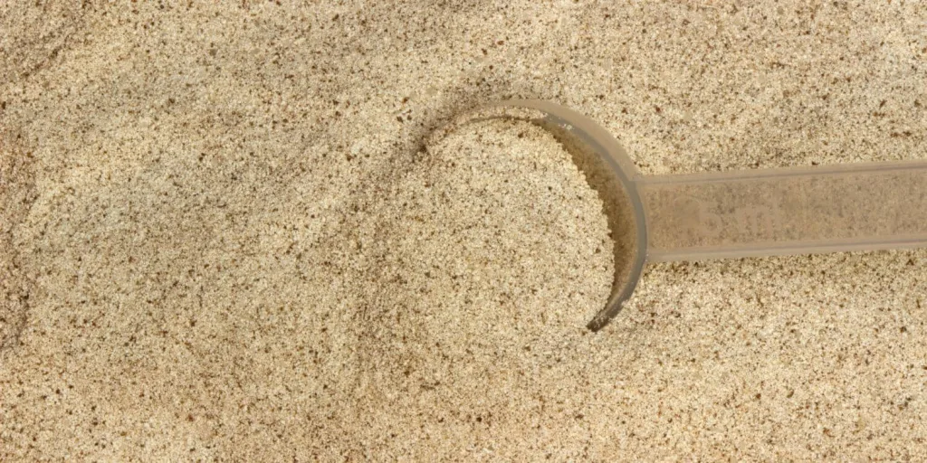 Bulk amount of chocolate whey protein isolate powder with a 5 ml scoop.
