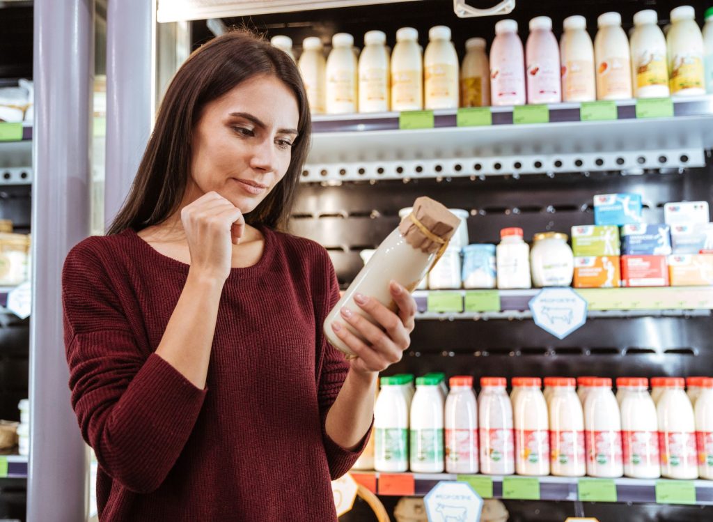 A consumer holding a bottle looking at the label details of the drink in a store.