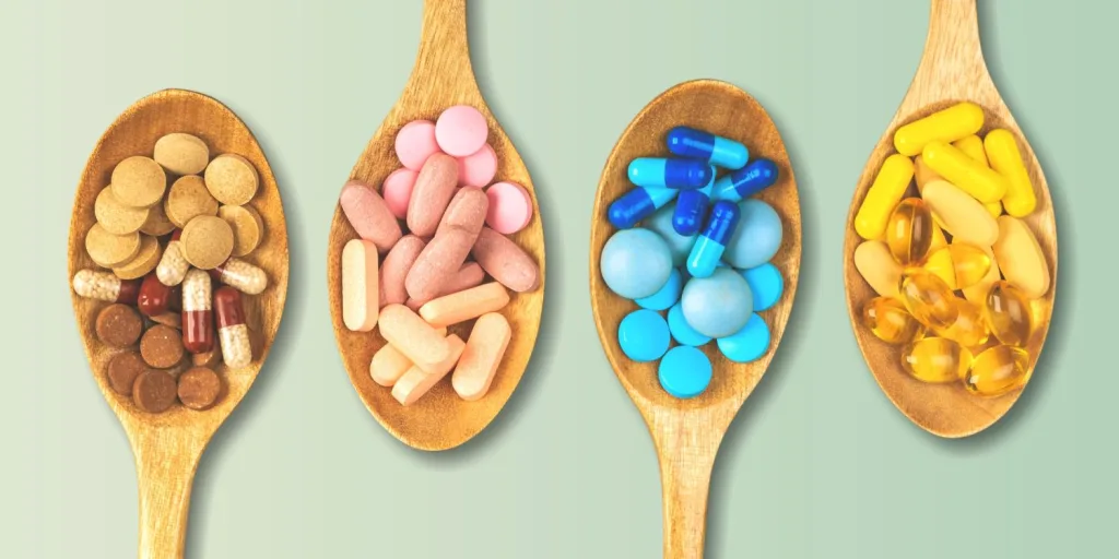 Wooden spoons filled with different supplements of alternating colors.