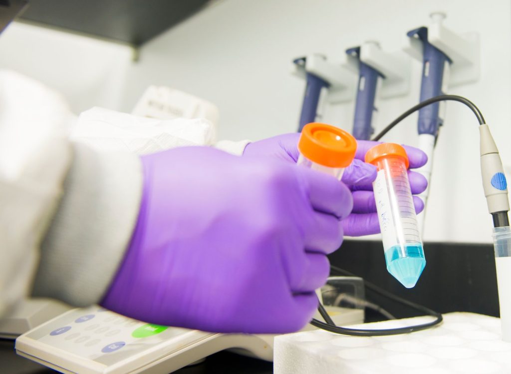 Gloved hands measuring a formulation in a laboratory setting.