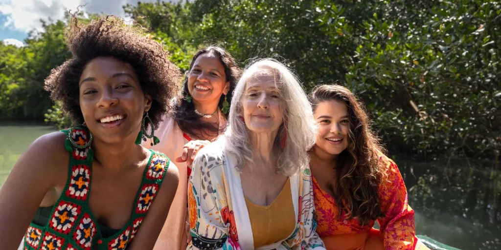 A group of diverse women smiling in front of nature.