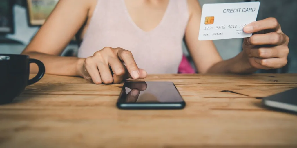 Closeup of woman online shopping, holding a credit card while tapping a smart phone.