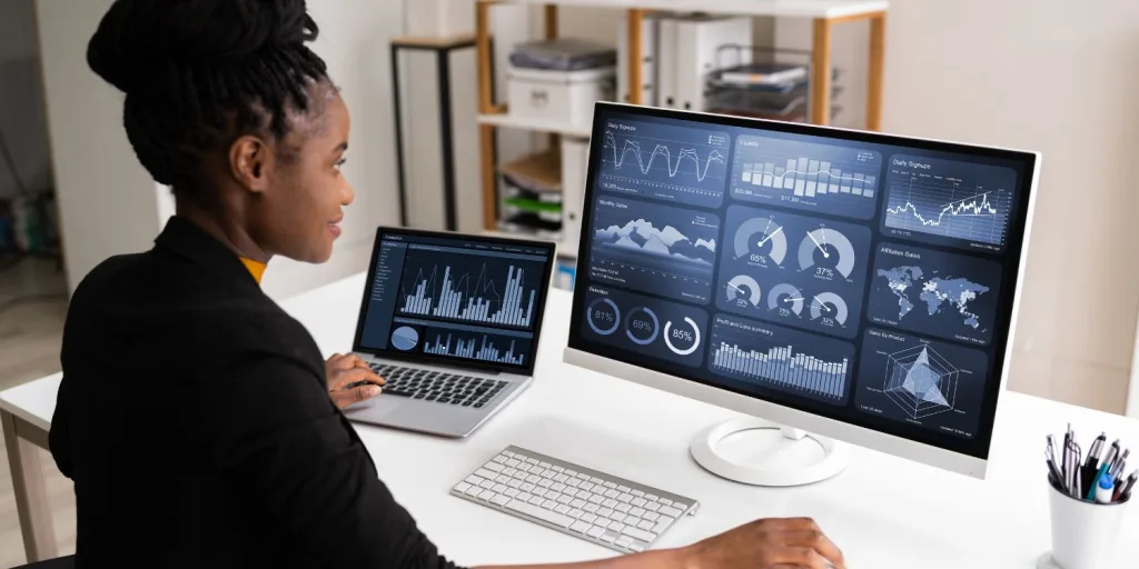 A female professional looking at different data metrics on a computer monitor.