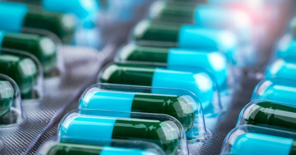 A close up shot of blue and green capsules inside a blister pack.