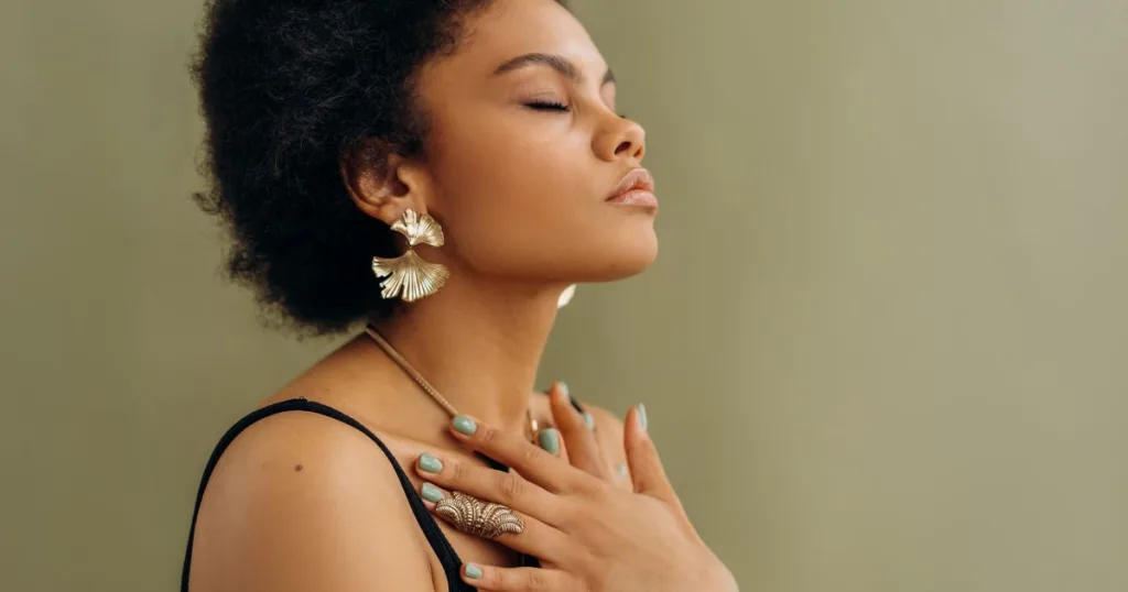 A woman meditating with her eyes closed and hands crossed on her chest.