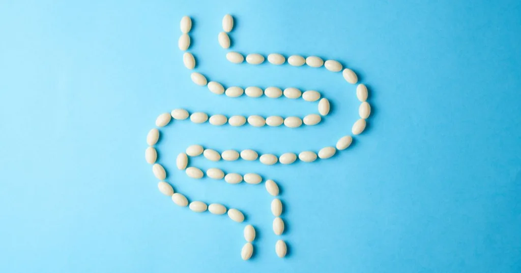 White pills arranged in the shape of the intestinal system against a blue background.