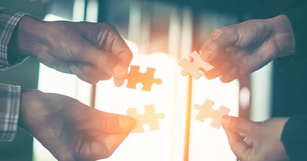 Two sets of hands holding puzzle pieces to fit together.