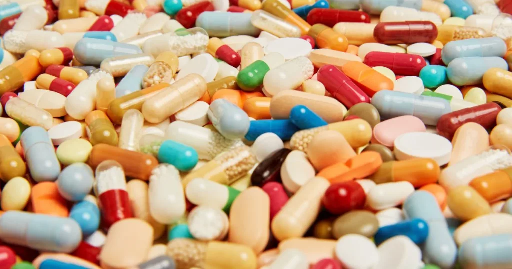 A mixture of differently colored tablets, capsules, and other types of solid dose supplement formats.