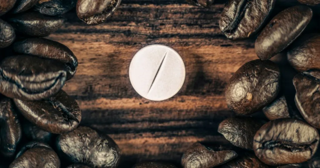 An image of a bisected caffeine tablet surrounded by coffee beans.