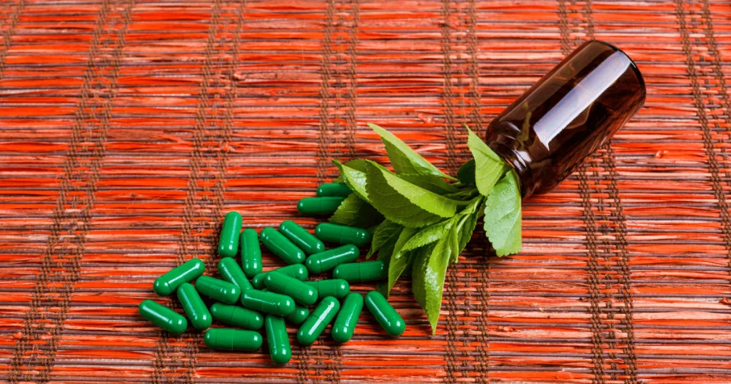 A supplement bottle containing botanicals with green pullulan capsules spilling out.