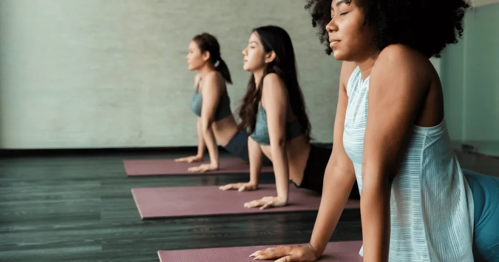 A group of three women on yoga mats in the upward facing dog yoga position.