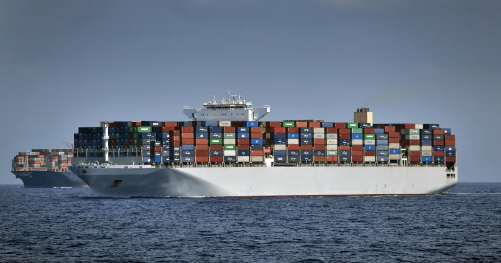 Shipping containers containing products being transported by boat in the ocean.
