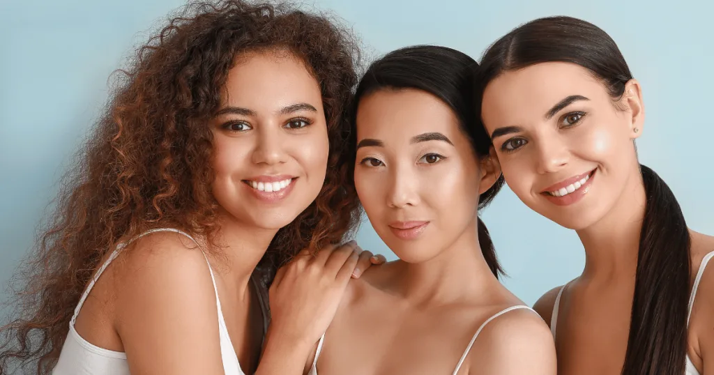 Three smiling women with clear skin, smiling.