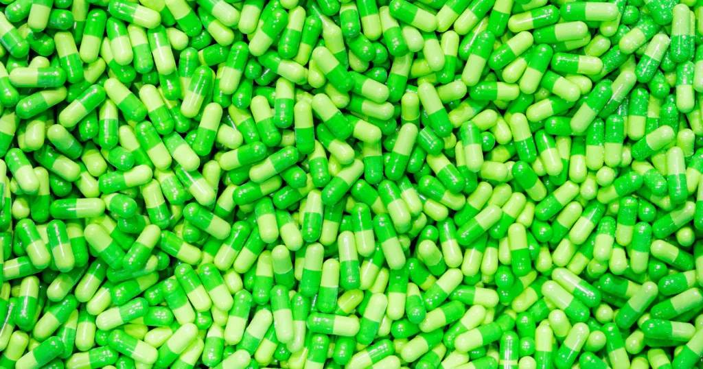 A close up shot of light green and darker green capsules.