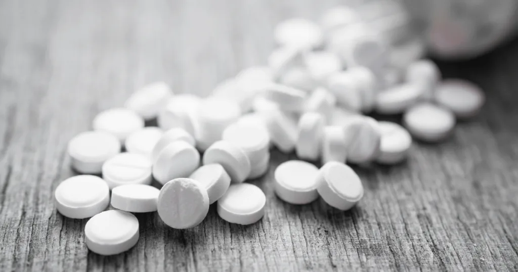 A black and white image of tablets spilled out on a surface, with some having capping and crumbling.