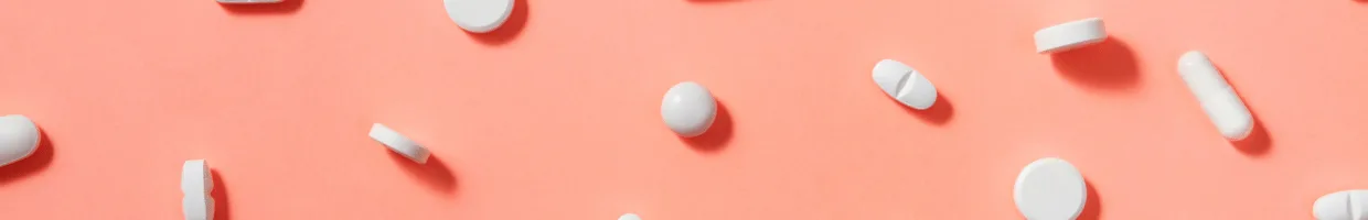 Scattered different types of tablets against a coral background.