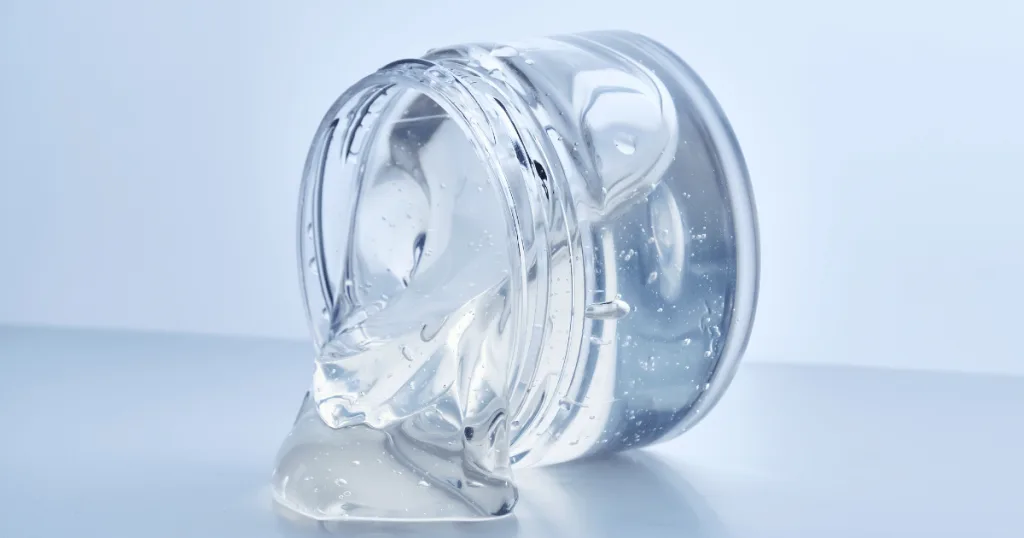 A personal care product container on its side, with the clear gel product slowly spilling out.