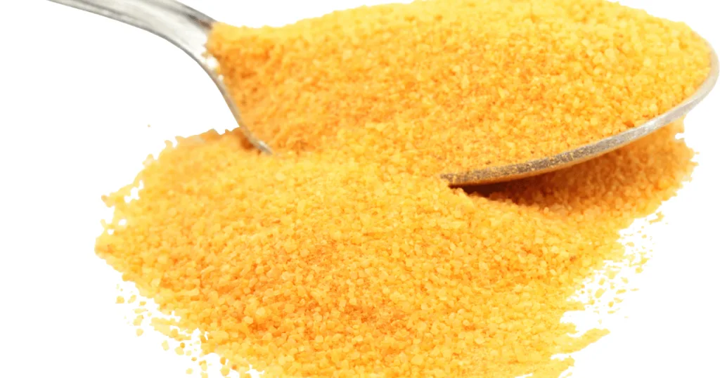 A metal spoon holding and resting upon a small pile of Ascorbic Acid