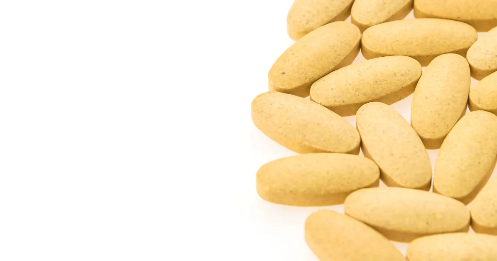 A small pile of yellow, oval-shaped vitamin c tablets.
