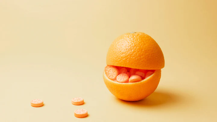 Two orange peel halves containing orange tablets with an orange slice shape.