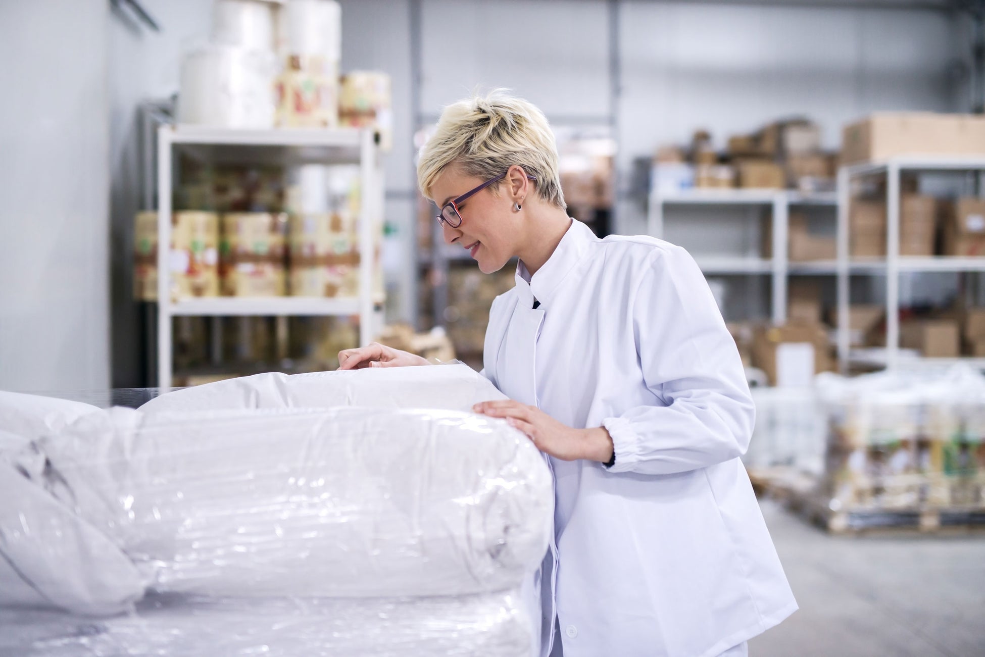 Woman inspecting pallet of wholesale ingredients in warehouse.